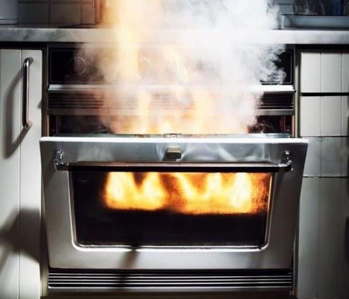 An open kitchen oven with flames shooting out of the opening. 
