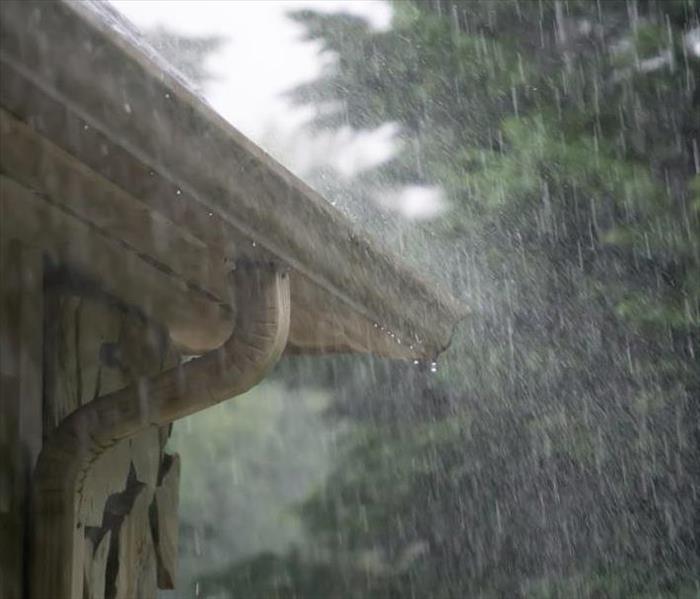 Picture of gutters overflowing at corner of home during a rain storm